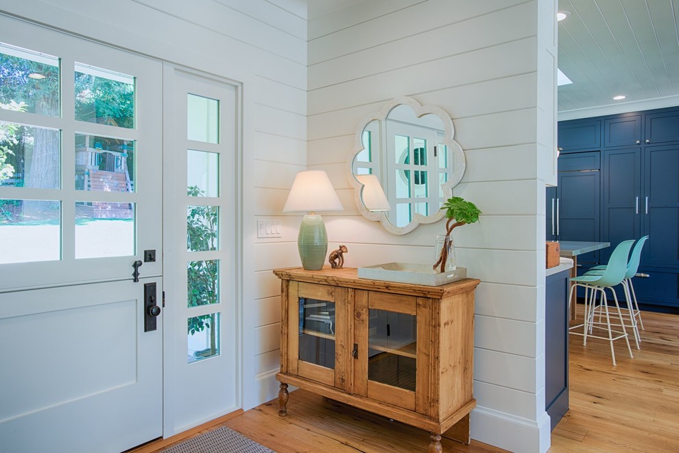 This is an example of a mid-sized country front door in San Francisco with white walls, light hardwood floors, a dutch front door, a white front door and beige floor.