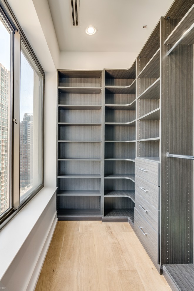 Design ideas for a mid-sized modern gender-neutral walk-in wardrobe in Chicago with open cabinets, dark wood cabinets, light hardwood floors and beige floor.