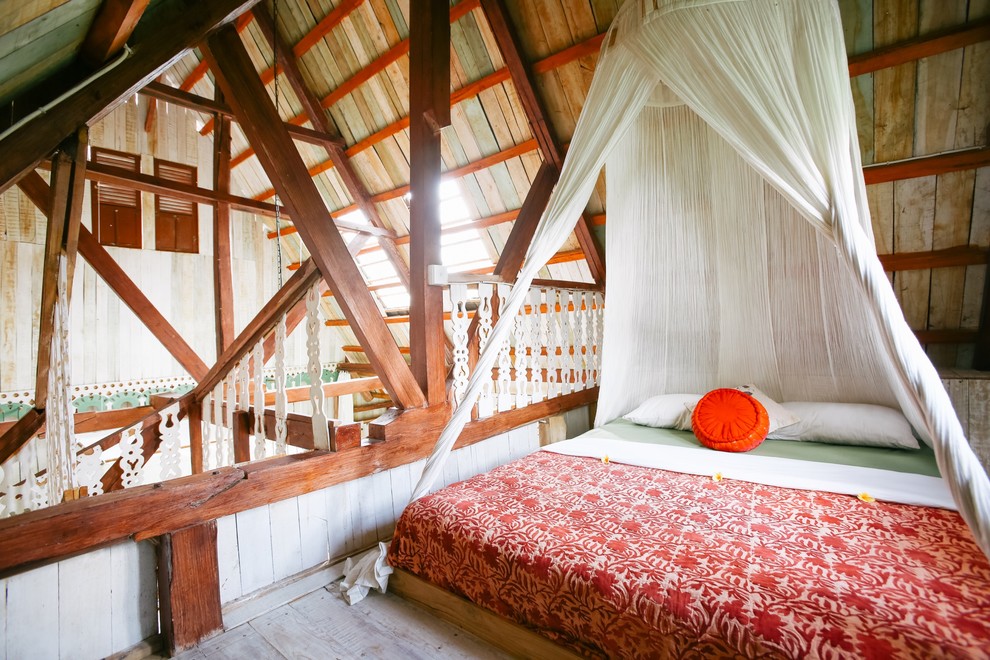 This is an example of a tropical bedroom in Singapore with beige walls, light hardwood floors and beige floor.