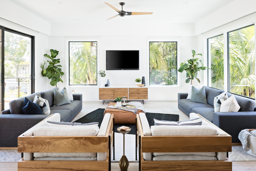 Photo of an expansive transitional open concept living room in Tampa with white walls, a wall-mounted tv and beige floor.