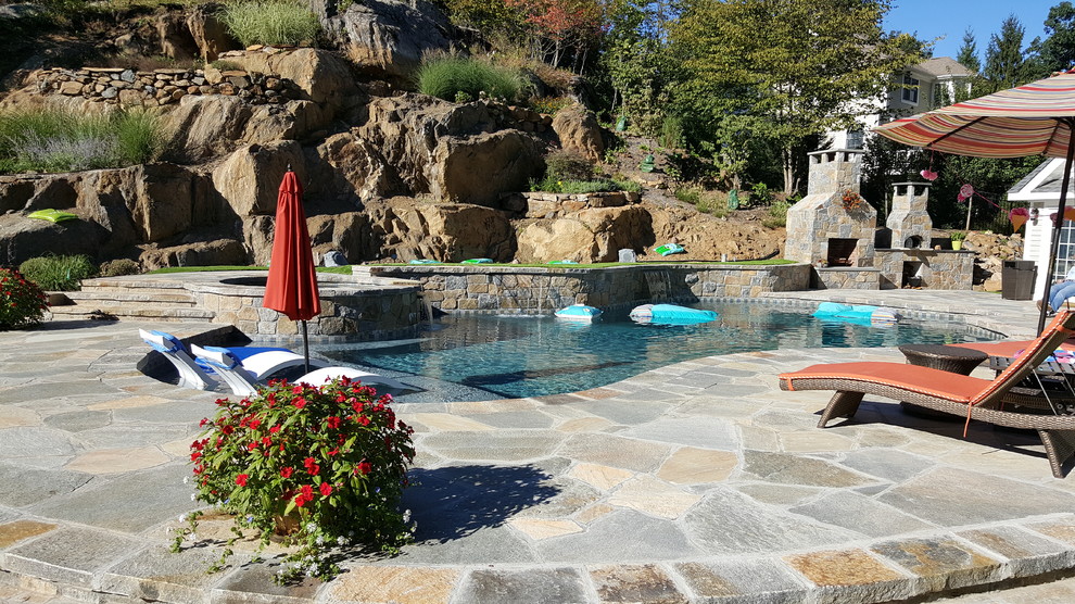 Inspiration for a mid-sized traditional backyard custom-shaped lap pool in New York with a hot tub and natural stone pavers.