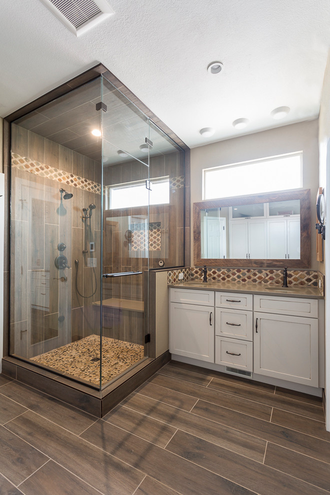 Inspiration for a mid-sized country master bathroom in Denver with shaker cabinets, beige cabinets, an alcove shower, brown tile, porcelain tile, beige walls, porcelain floors, an undermount sink, engineered quartz benchtops, brown floor, a hinged shower door and brown benchtops.