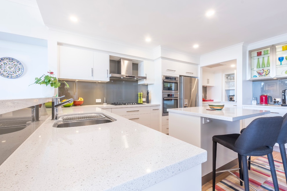 Inspiration for a contemporary kitchen in Perth with an undermount sink, flat-panel cabinets, white cabinets, quartz benchtops, grey splashback, glass sheet splashback, stainless steel appliances, with island and white benchtop.