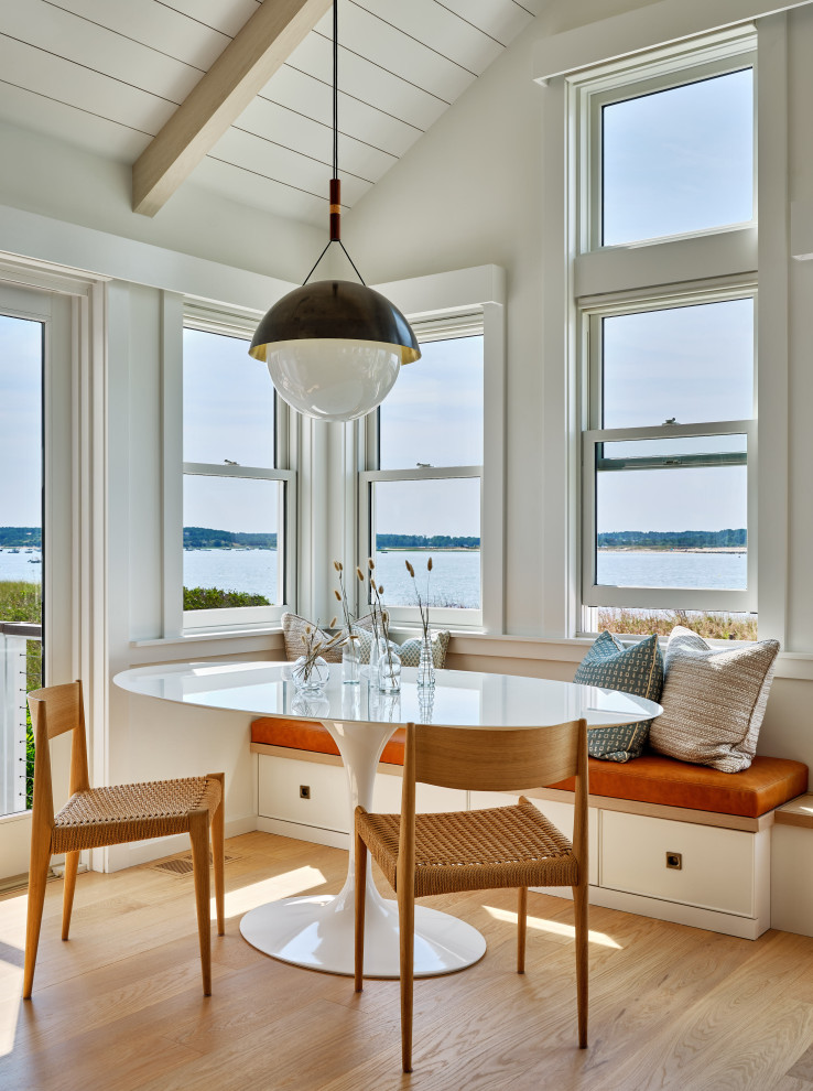 Inspiration for a small coastal dining room in Boston with banquette seating, white walls, light hardwood flooring, beige floors, exposed beams and wood walls.