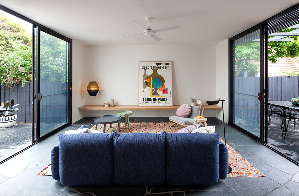 This is an example of a midcentury living room in Melbourne with white walls and black floor.