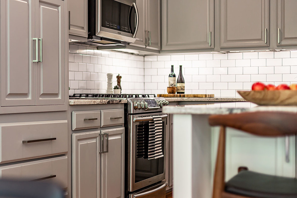 Example of a mid-sized transitional l-shaped medium tone wood floor and brown floor eat-in kitchen design in Richmond with a farmhouse sink, gray cabinets, granite countertops, white backsplash, ceramic backsplash, stainless steel appliances, an island and multicolored countertops