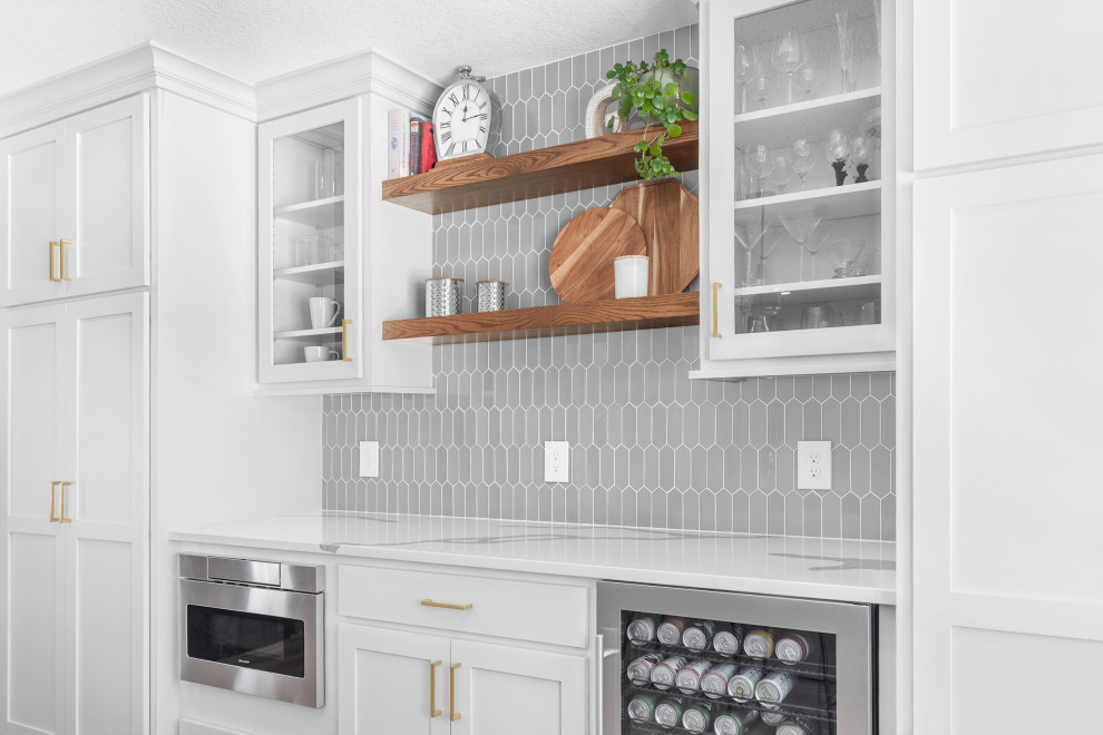 Eat-in kitchen - mid-sized transitional l-shaped light wood floor and brown floor eat-in kitchen idea in Minneapolis with an undermount sink, recessed-panel cabinets, gray cabinets, quartz countertops, gray backsplash, glass tile backsplash, stainless steel appliances, an island and white countertops