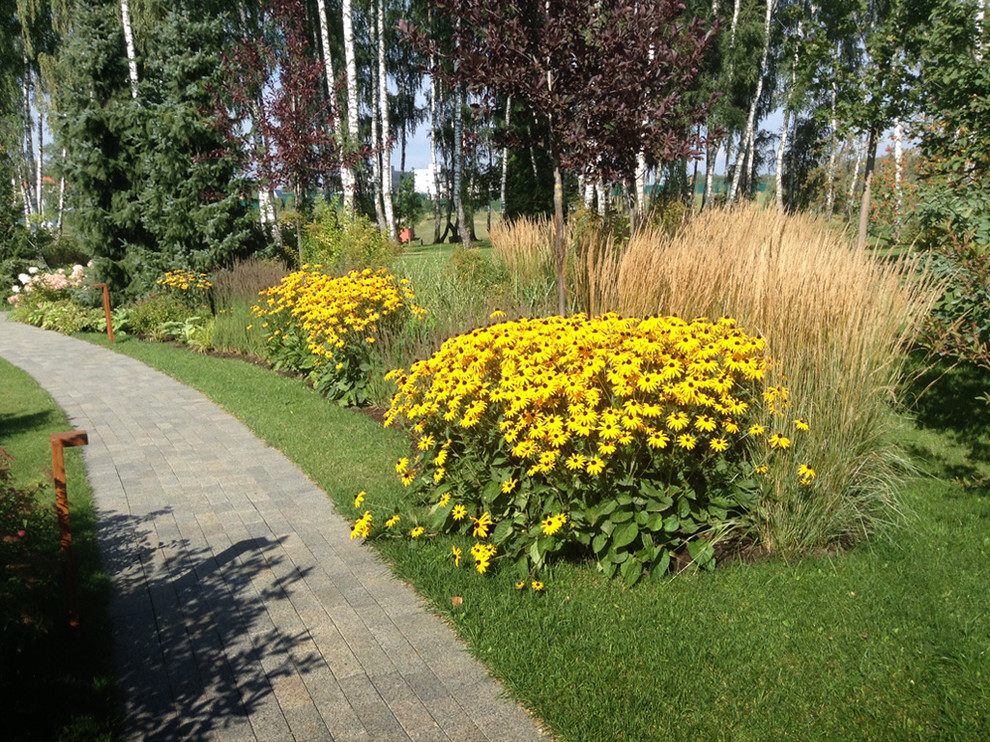 Цветник и садовые светильники вдоль прогулочной дорожки из гранитной брусчатки