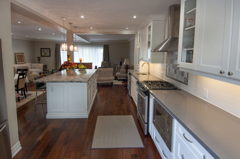 Open concept kitchen - large transitional u-shaped medium tone wood floor open concept kitchen idea in Toronto with a double-bowl sink, shaker cabinets, white cabinets, quartzite countertops, white backsplash, ceramic backsplash, stainless steel appliances and an island
