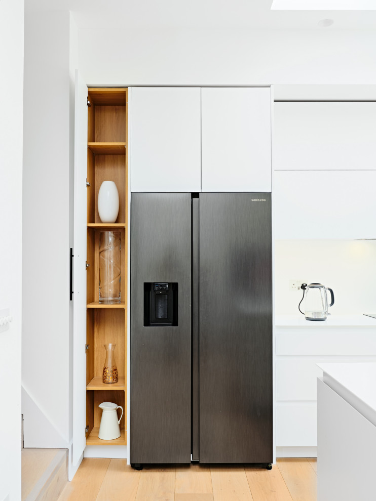Diseño de cocina comedor lineal contemporánea de tamaño medio con armarios con paneles lisos, puertas de armario blancas, una isla y encimeras blancas