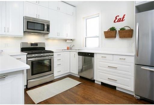 This is an example of a contemporary u-shaped eat-in kitchen in Boston with white cabinets, white splashback, stainless steel appliances, dark hardwood floors and no island.