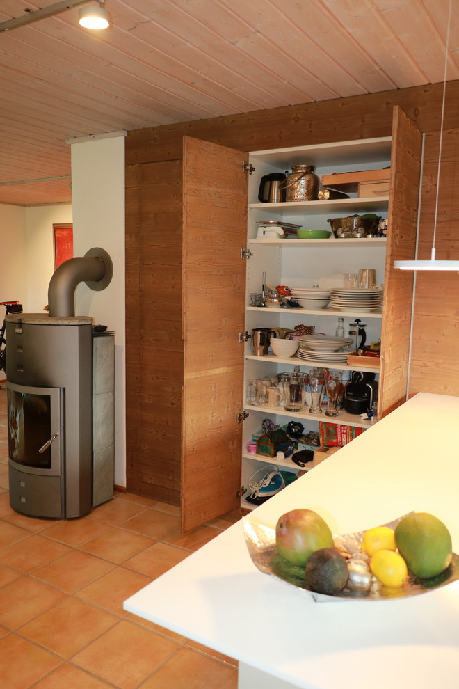 Mittelgroßes, Repräsentatives, Offenes Country Wohnzimmer mit weißer Wandfarbe, Terrakottaboden, Kamin, Kaminumrandung aus Metall, verstecktem TV und rotem Boden in München