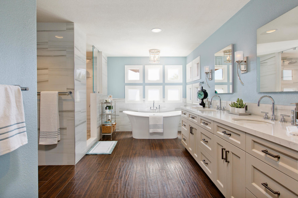 This is an example of a large traditional master bathroom in Denver with recessed-panel cabinets, white cabinets, a freestanding tub, an open shower, a wall-mount toilet, yellow tile, porcelain tile, blue walls, porcelain floors, an undermount sink and engineered quartz benchtops.