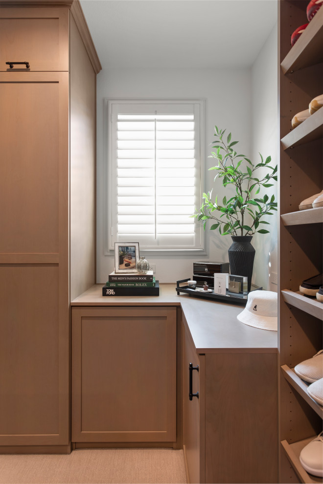 Design ideas for a mid-sized traditional gender-neutral storage and wardrobe in Los Angeles with shaker cabinets, medium wood cabinets, carpet and black floor.