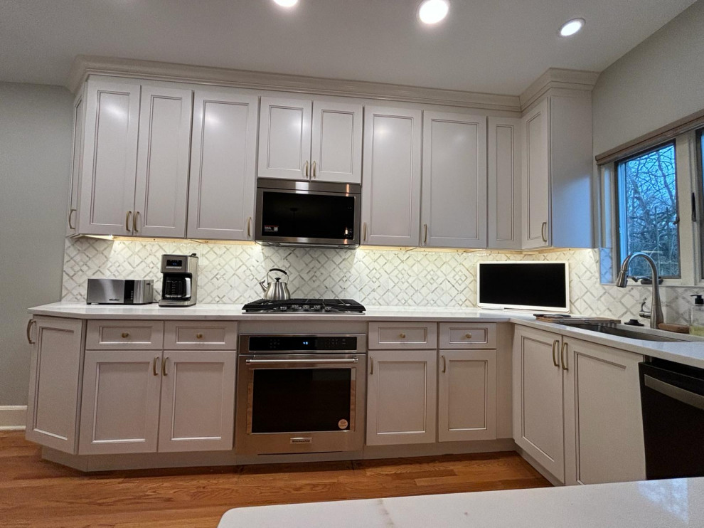 Inspiration for a large contemporary galley eat-in kitchen in Philadelphia with an undermount sink, shaker cabinets, beige cabinets, marble benchtops, multi-coloured splashback, marble splashback, stainless steel appliances, medium hardwood floors, with island and white benchtop.