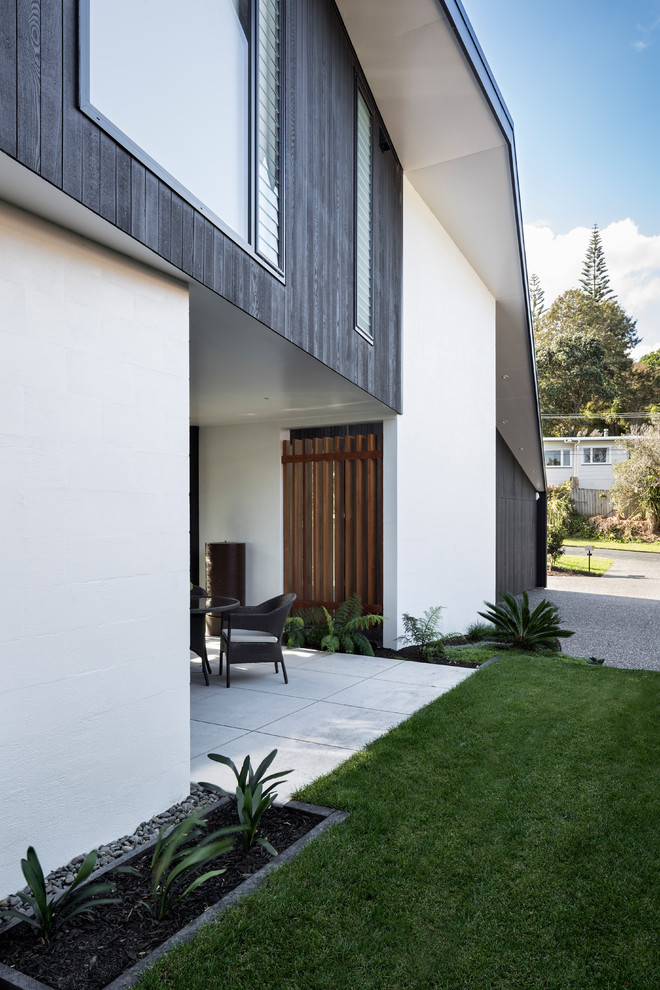 Inspiration for a mid-sized contemporary two-storey black house exterior in Auckland with mixed siding and a metal roof.