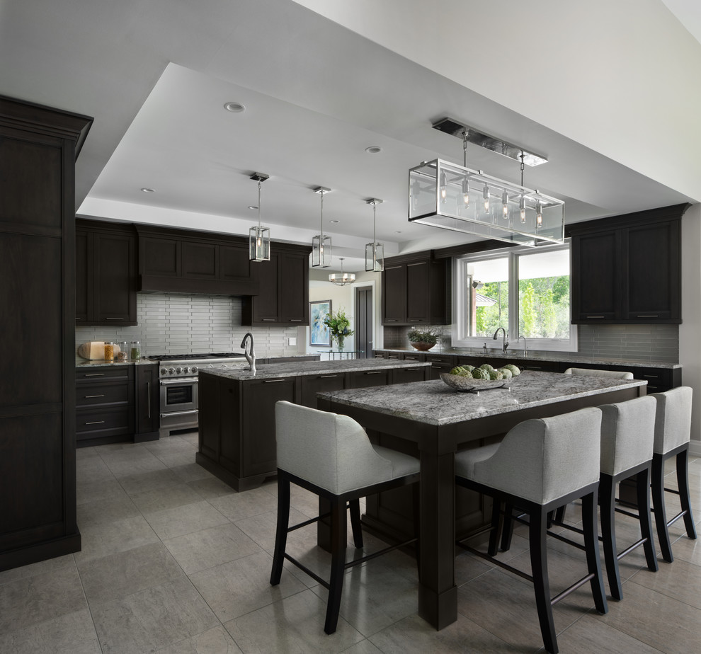 Inspiration for a transitional u-shaped kitchen in Detroit with recessed-panel cabinets, dark wood cabinets, grey splashback, matchstick tile splashback, stainless steel appliances, multiple islands, grey floor and grey benchtop.