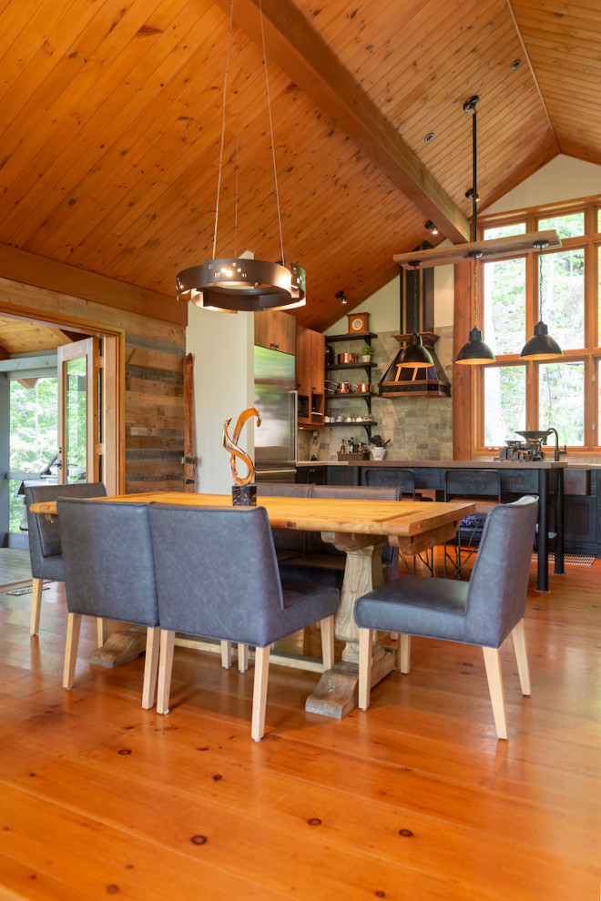 Mid-sized country kitchen/dining combo in Montreal with white walls, medium hardwood floors, a stone fireplace surround and orange floor.