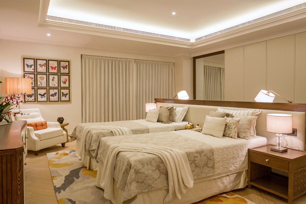 This is an example of a large transitional bedroom in Bengaluru with beige walls and light hardwood floors.