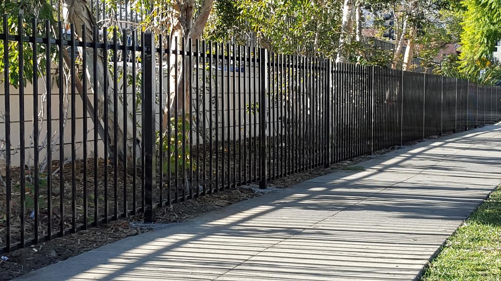Mid-sized industrial front yard partial sun xeriscape in Los Angeles with mulch and a metal fence for summer.