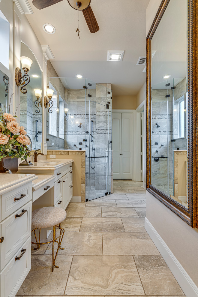 Traditional bathroom in Dallas with raised-panel cabinets, white cabinets, a built-in shower, beige tiles, porcelain tiles, porcelain flooring, a submerged sink, marble worktops, beige floors, a hinged door, beige worktops, an enclosed toilet, double sinks and a built in vanity unit.