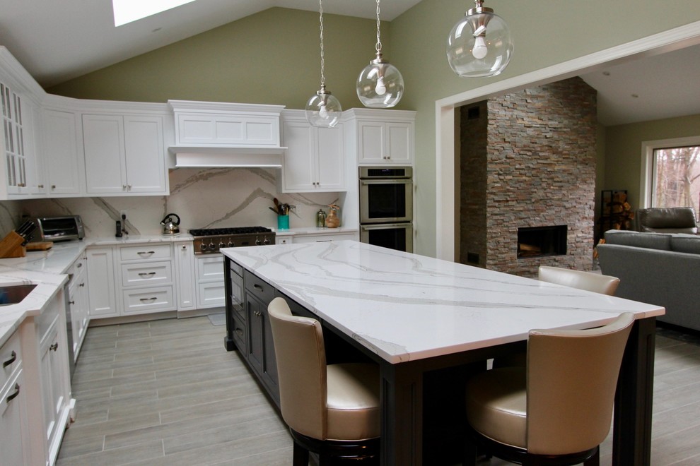 Photo of a large transitional eat-in kitchen in New York with an undermount sink, shaker cabinets, grey cabinets, quartz benchtops, stone slab splashback, stainless steel appliances, porcelain floors and with island.