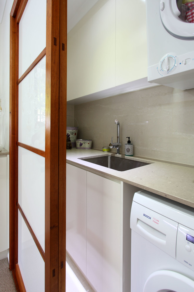 Inspiration for a small asian l-shaped laundry cupboard in Brisbane with an undermount sink, flat-panel cabinets, white cabinets, quartz benchtops, grey walls, porcelain floors, an integrated washer and dryer, white floor and grey benchtop.