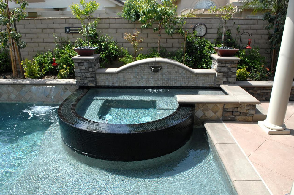 Example of a mid-sized transitional backyard concrete paver and custom-shaped lap hot tub design in Orange County