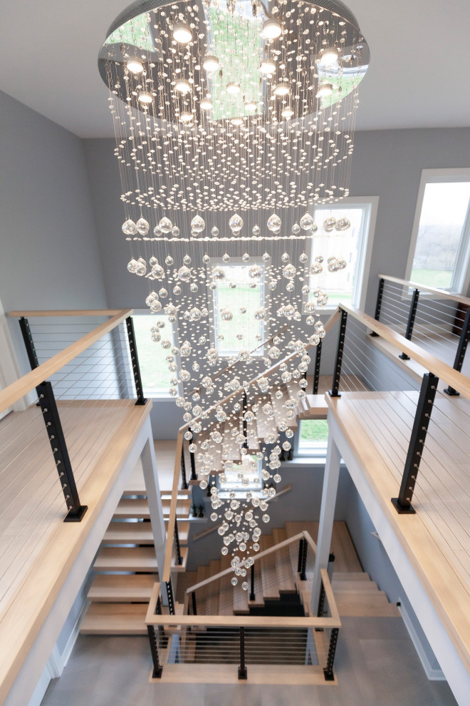 Источник вдохновения для домашнего уюта: большая металлическая лестница на больцах в стиле модернизм с деревянными ступенями и перилами из тросов