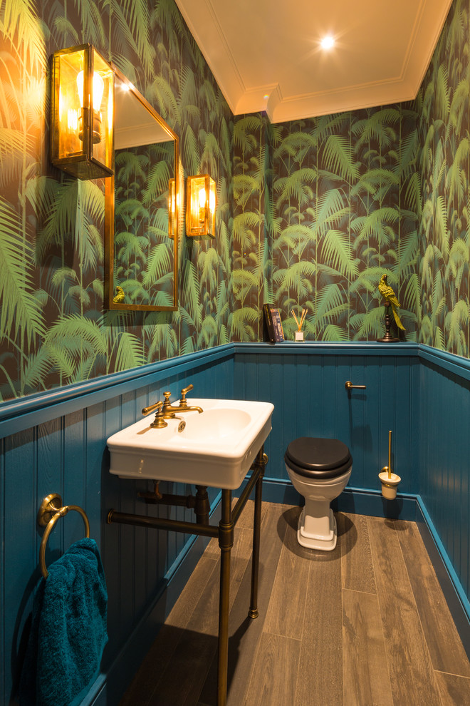ロンドンにある小さなおしゃれなトイレ・洗面所 (一体型トイレ	、青い壁、コンソール型シンク、茶色い床) の写真