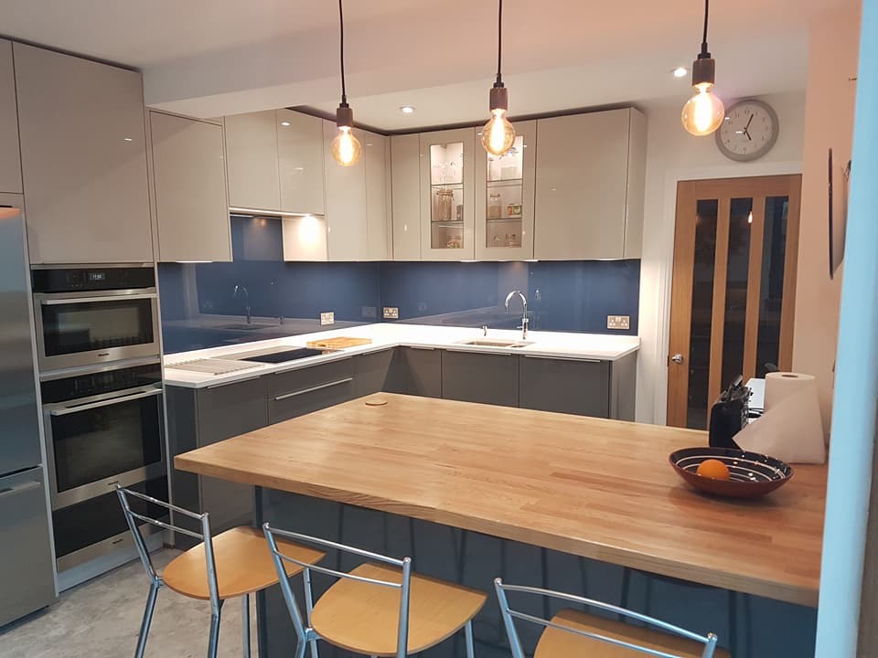 Mid-sized contemporary l-shaped eat-in kitchen in Kent with a drop-in sink, flat-panel cabinets, grey cabinets, quartzite benchtops, blue splashback, glass sheet splashback, stainless steel appliances and with island.