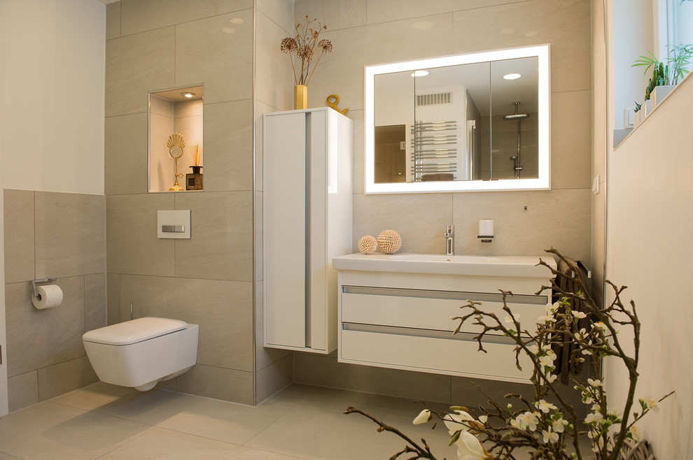 This is an example of a large contemporary bathroom in Dortmund with white cabinets, a wall-mount toilet, beige tile, limestone floors, a wall-mount sink, flat-panel cabinets, cement tile, solid surface benchtops and with a sauna.