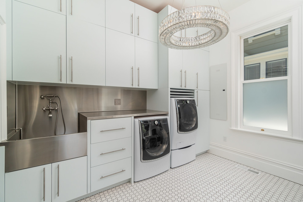 Traditional laundry room in San Francisco with flat-panel cabinets, white cabinets, stainless steel benchtops, white walls, porcelain floors, a side-by-side washer and dryer and white floor.