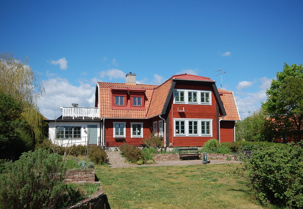 Design ideas for a country two-storey red house exterior in Other with wood siding, a gambrel roof and a mixed roof.