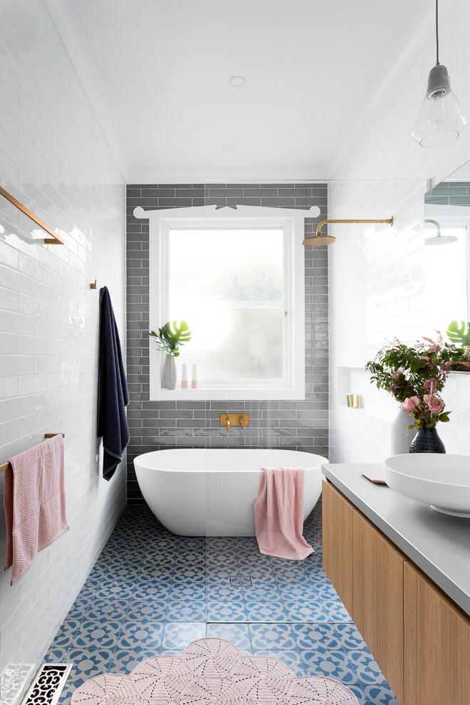 Inspiration for a large contemporary master bathroom in Melbourne with flat-panel cabinets, medium wood cabinets, a freestanding tub, an alcove shower, a two-piece toilet, ceramic tile, grey walls, ceramic floors, a vessel sink, concrete benchtops, blue floor, a hinged shower door and grey benchtops.