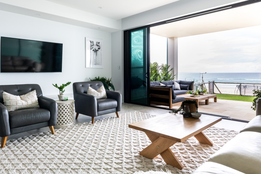 This is an example of a large beach style open concept living room in Gold Coast - Tweed with white walls, porcelain floors, a wall-mounted tv and multi-coloured floor.
