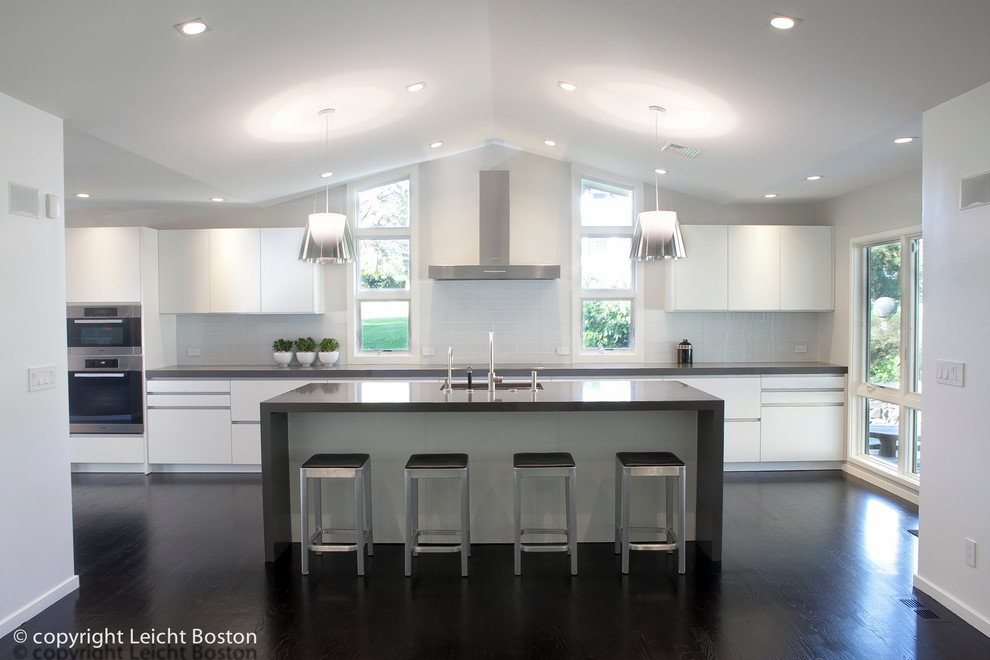 Photo of a large contemporary single-wall eat-in kitchen in Boston with an undermount sink, flat-panel cabinets, white cabinets, white splashback, subway tile splashback, stainless steel appliances, dark hardwood floors and with island.