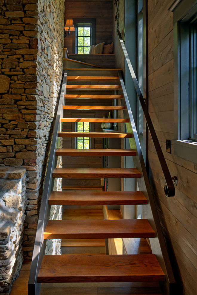 This is an example of a large arts and crafts wood straight staircase in Charlotte with open risers and metal railing.