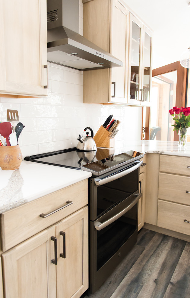 Inspiration for a mid-sized transitional u-shaped vinyl floor and brown floor enclosed kitchen remodel with an undermount sink, flat-panel cabinets, beige cabinets, quartz countertops, white backsplash, subway tile backsplash, black appliances, a peninsula and white countertops