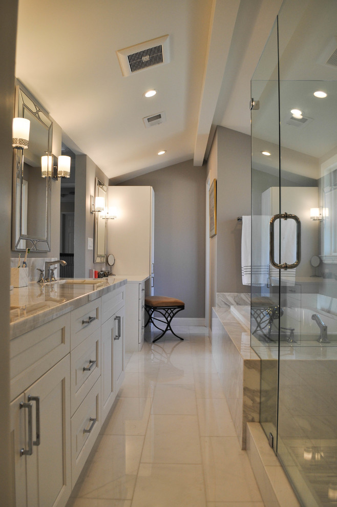 This is an example of a large traditional master bathroom in San Francisco with recessed-panel cabinets, white cabinets, a drop-in tub, a corner shower, a two-piece toilet, white tile, marble, brown walls, marble floors, an undermount sink, marble benchtops, white floor and a hinged shower door.