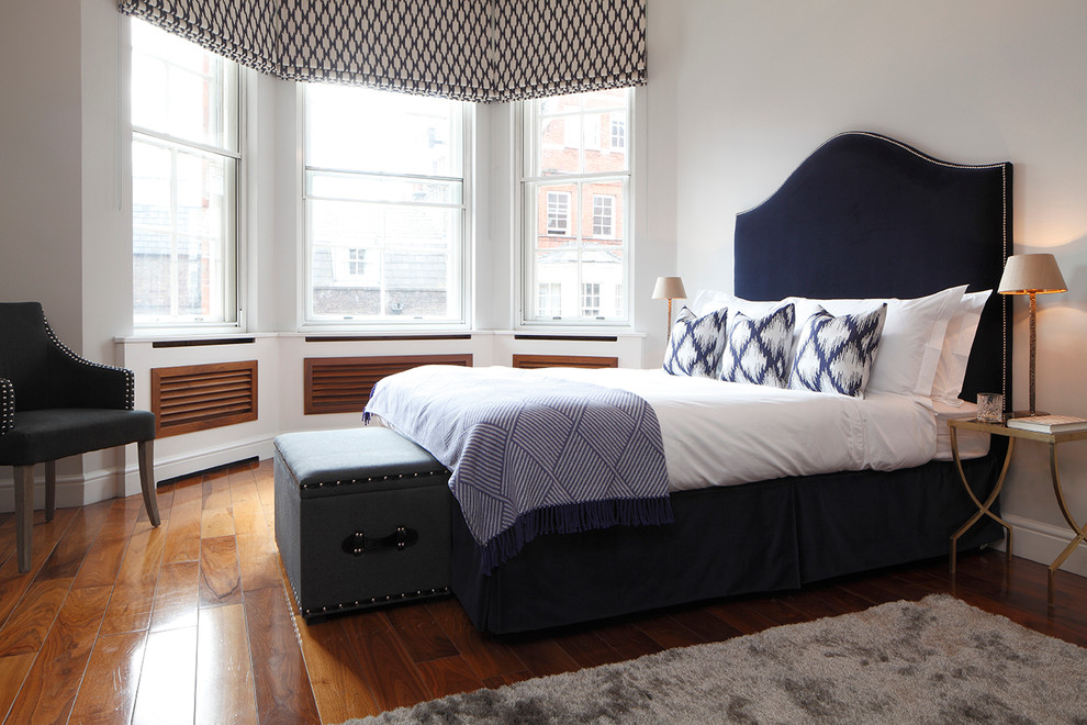 Photo of a transitional bedroom in London with white walls and medium hardwood floors.
