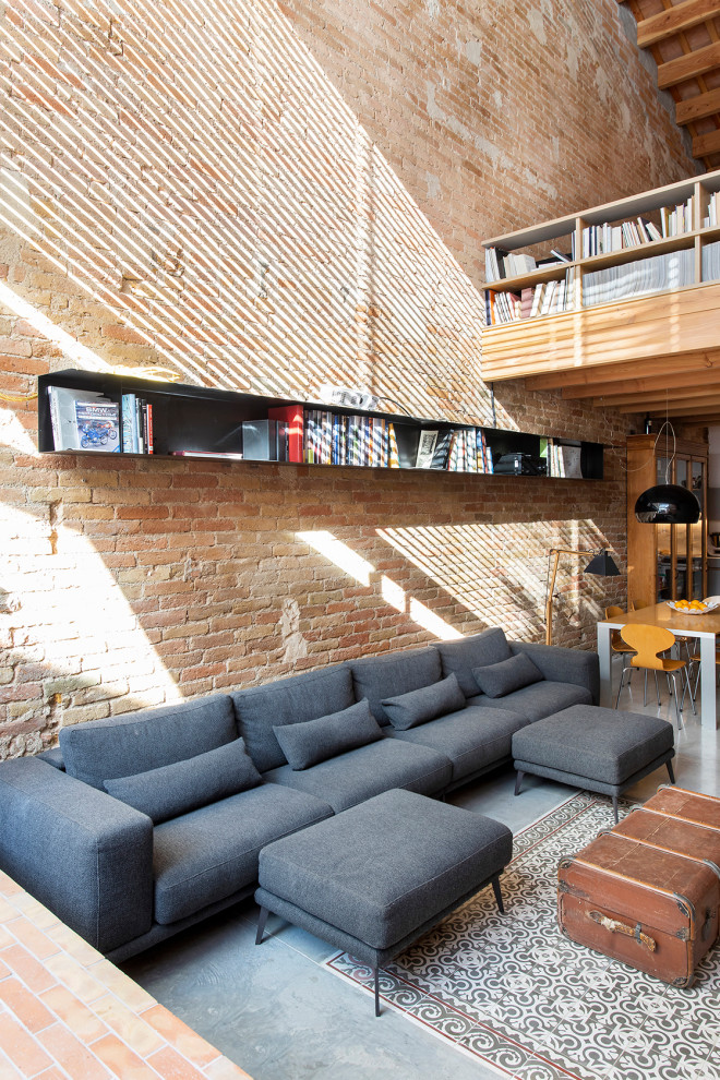 This is an example of a large industrial open concept living room in Barcelona with red walls, concrete floors, blue floor, vaulted and brick walls.