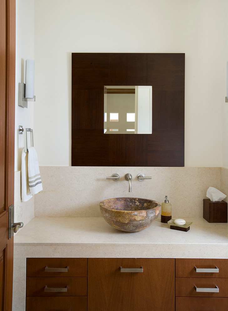 This is an example of a contemporary powder room in Houston with a vessel sink, flat-panel cabinets, medium wood cabinets, white walls and beige benchtops.