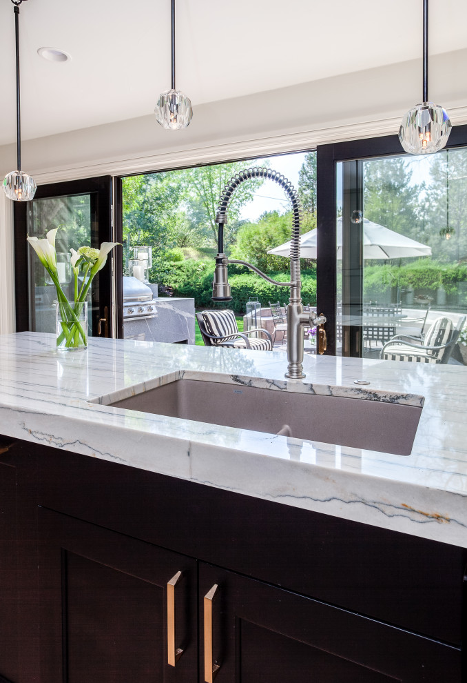 This is an example of a large contemporary open plan kitchen in Denver with a submerged sink, shaker cabinets, grey cabinets, quartz worktops, white splashback, marble splashback, black appliances, ceramic flooring, beige floors and white worktops.