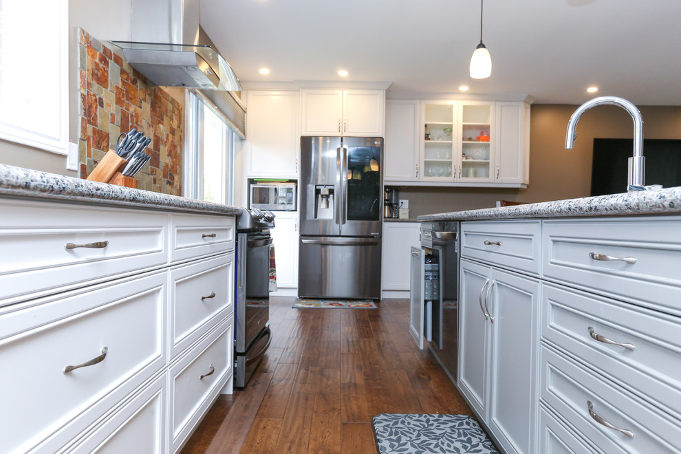 Design ideas for a large traditional galley eat-in kitchen in Toronto with an undermount sink, recessed-panel cabinets, white cabinets, granite benchtops, multi-coloured splashback, slate splashback, stainless steel appliances, medium hardwood floors, with island and brown floor.