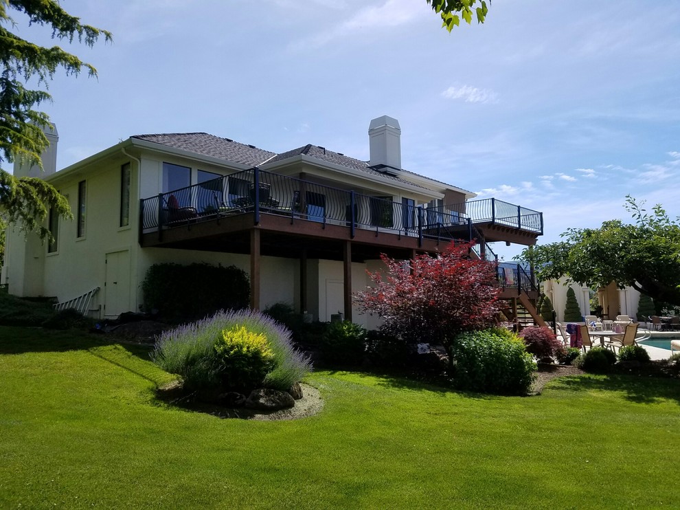 Huge transitional backyard deck photo with a fire pit and a roof extension