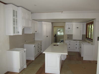 Mid-sized country l-shaped kitchen pantry in Brisbane with white cabinets, wood benchtops and with island.
