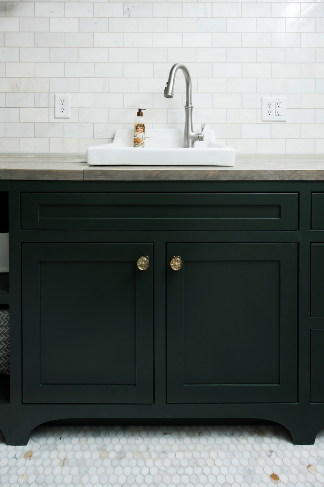 This is an example of a mid-sized traditional galley dedicated laundry room in Indianapolis with shaker cabinets, green cabinets, marble floors, white floor, a drop-in sink, wood benchtops, green walls and a side-by-side washer and dryer.