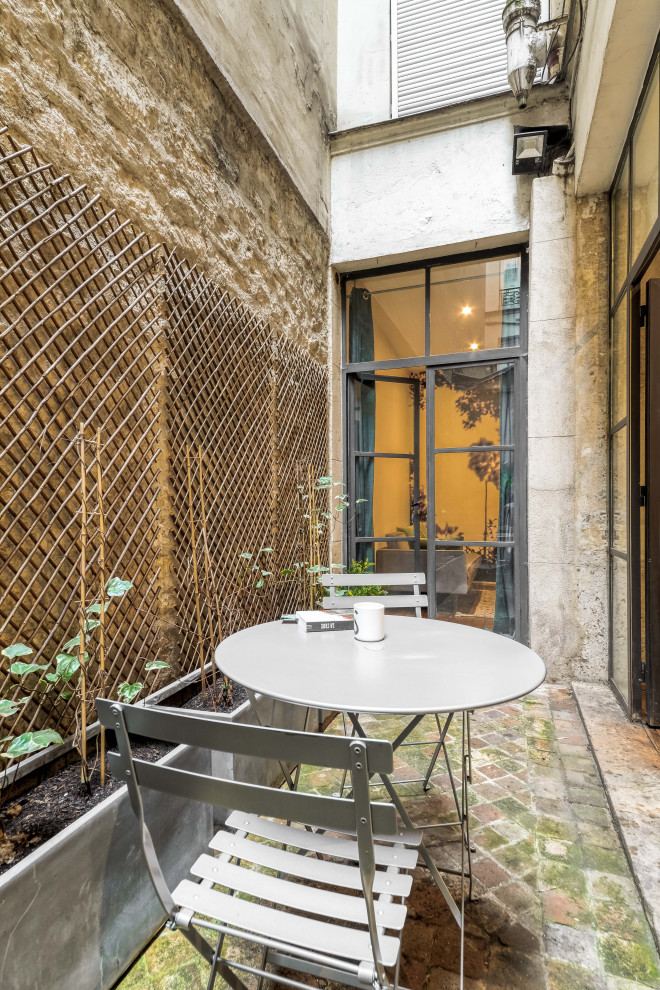 Inspiration for a mid-sized contemporary courtyard patio in Paris with natural stone pavers and no cover.