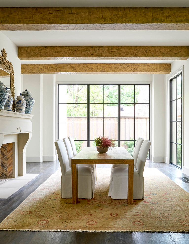 Inspiration for a mediterranean separate dining room in Dallas with white walls, dark hardwood floors, a standard fireplace and a stone fireplace surround.